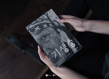 Person holding a book with a black and white cover featuring text and a face.